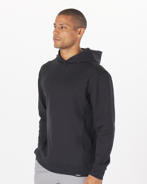 Black pullover hoodie with drawstring hood, shown on male model in side profile view.
