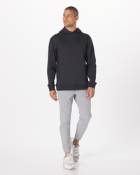 Black pullover hoodie with drawstring hood and ribbed cuffs, shown on model with gray pants.