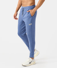 Men's heather blue joggers with drawstring waist, side pockets, and branded label patch on thigh.