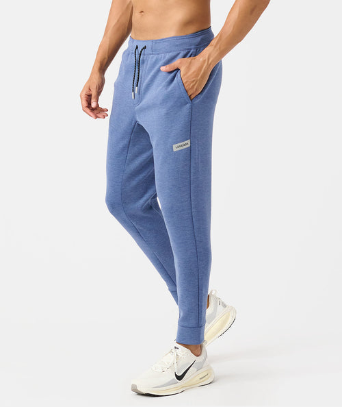 Men's heather blue joggers with drawstring waist, side pockets, and branded label patch on thigh.