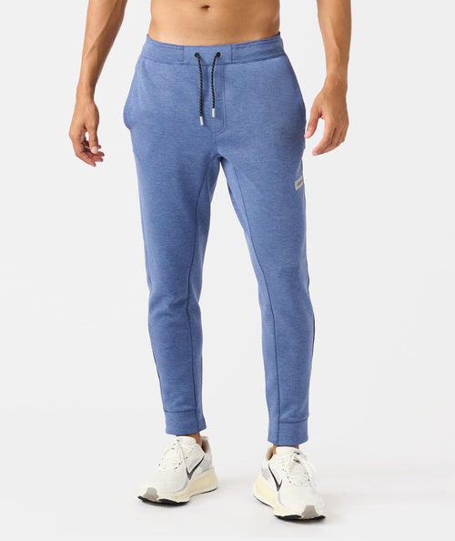 Man wearing heather blue joggers with drawstring waist and white sneakers.