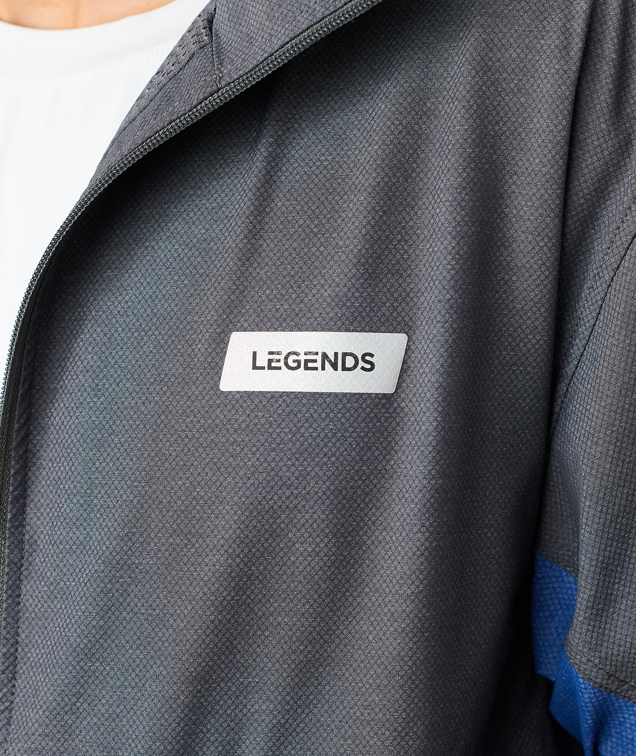 Charcoal full-zip jacket with textured fabric, white "Legends" label, and blue panel visible on sleeve.