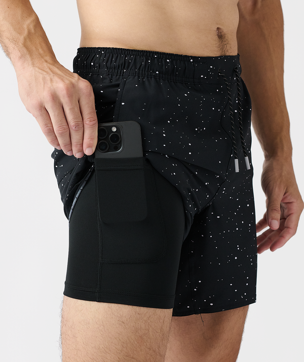 Black shorts with white splatter pattern and side pocket holding phone.