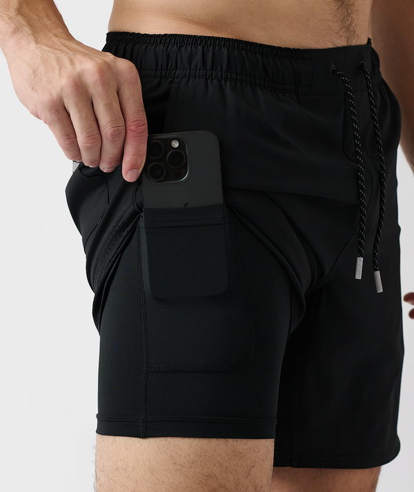 Black shorts with elasticated waistband, drawstring, and side pocket holding a smartphone.