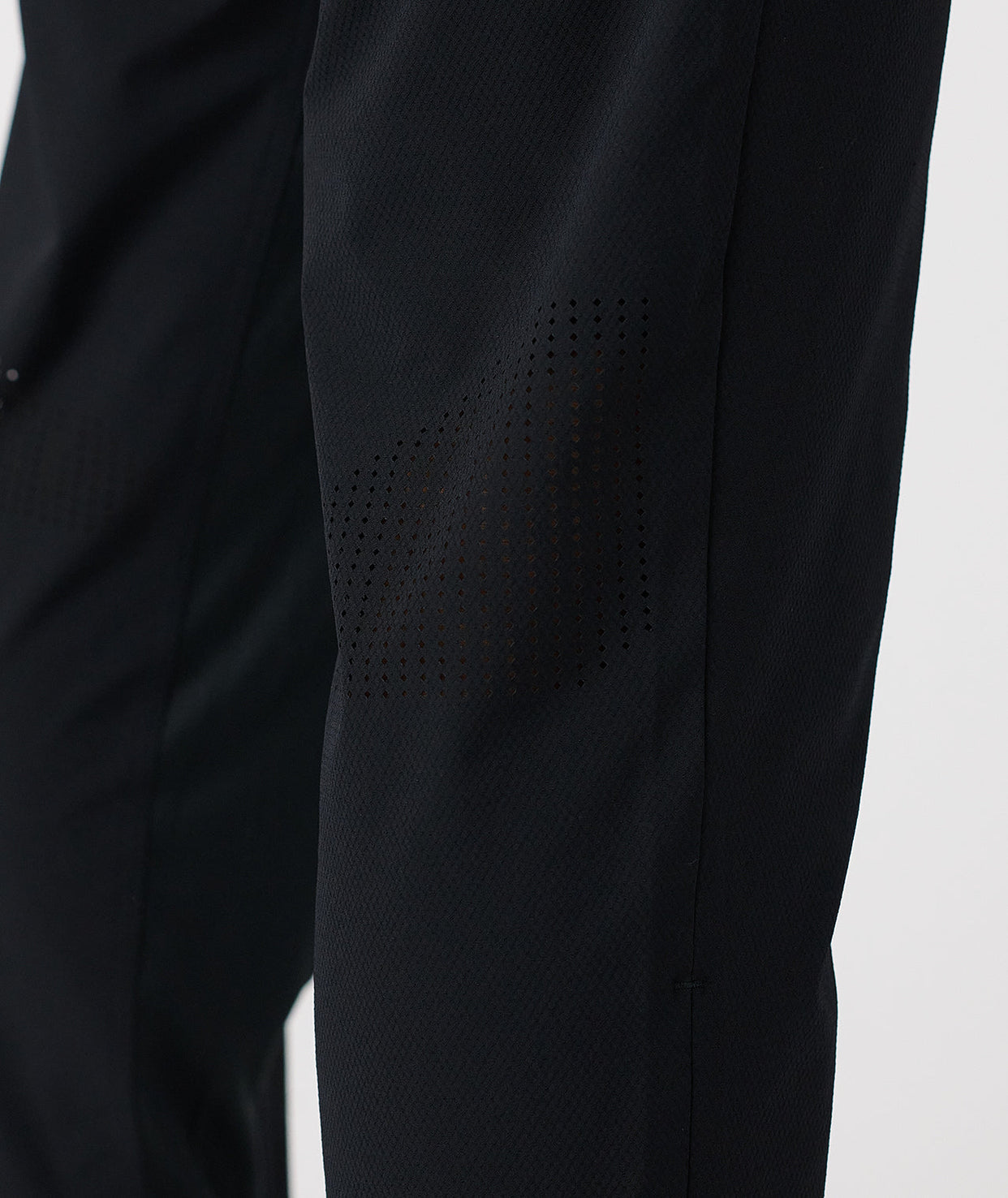 Black pant with textured fabric and perforated ventilation panel on thigh.