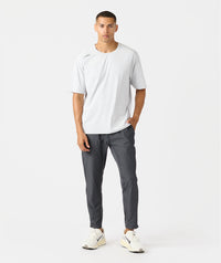 Man wearing charcoal gray pants with drawstring waist and white short-sleeve shirt.