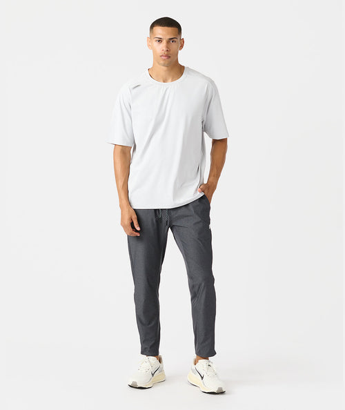 Man wearing charcoal gray pants with drawstring waist and white short-sleeve shirt.