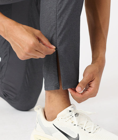 Charcoal gray tapered pant with textured fabric shown at ankle length on model wearing white sneakers.