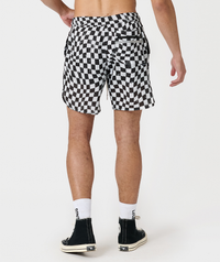 Black and white warped checkerboard mesh shorts with side pockets, shown on male model from waist down.