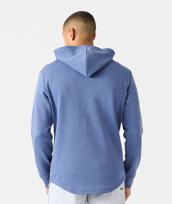 Blue heather quarter-zip hoodie with kangaroo pocket, shown from back on model wearing white pants.