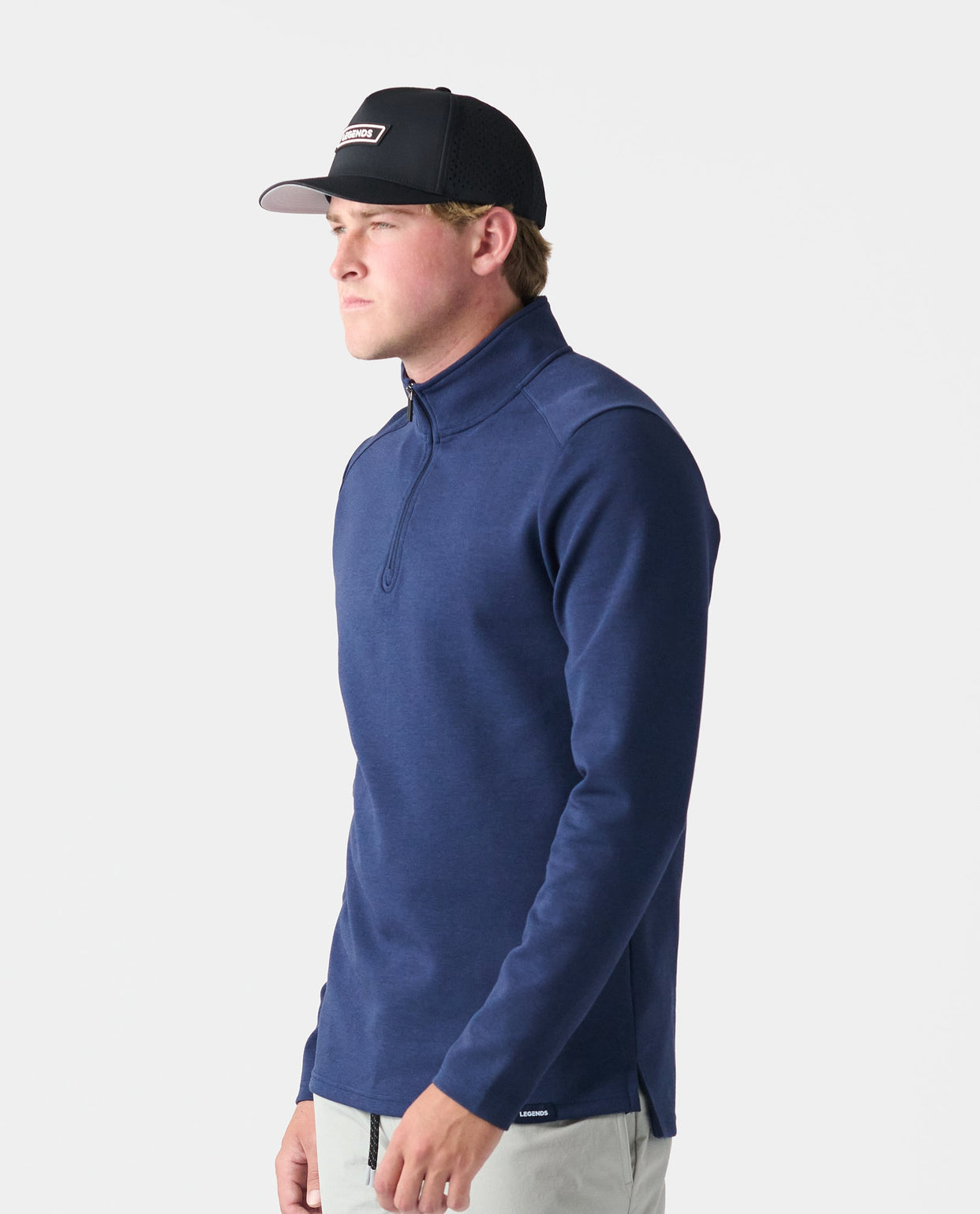 Navy quarter-zip scuba sweatshirt with mock neck, worn with black baseball cap and light pants.