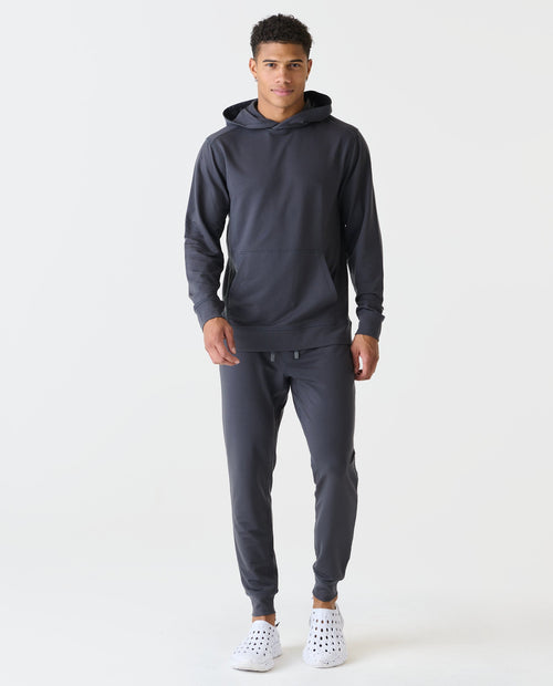 Charcoal gray hoodie with kangaroo pocket and matching joggers worn by model with white sneakers.